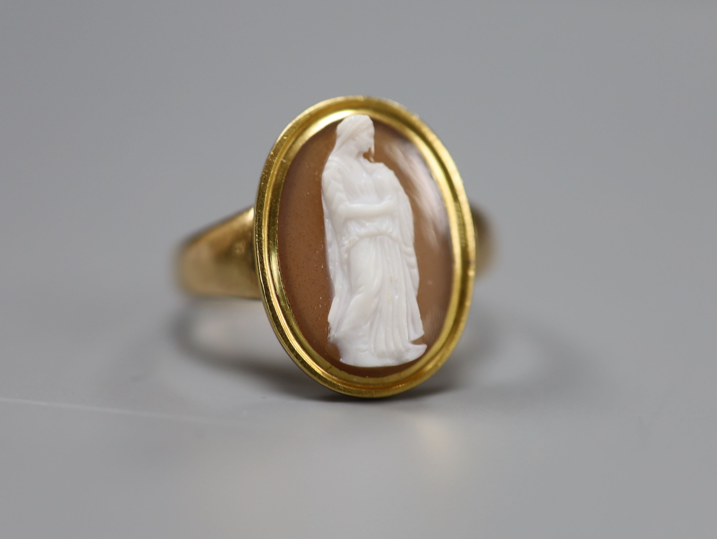 A 19th century yellow metal and oval cameo hardstone ring, carved with the figure of a lady with an urn, size R, gross 4.6 grams.